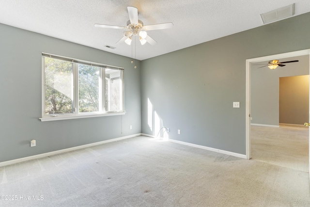 spare room featuring a textured ceiling, light colored carpet, and ceiling fan