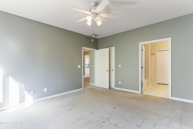 unfurnished bedroom featuring ceiling fan, light colored carpet, and ensuite bath