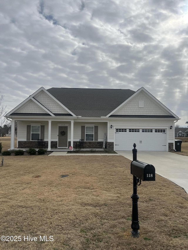 craftsman-style home featuring covered porch, a front yard, and a garage