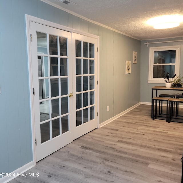 interior space with ornamental molding, french doors, a textured ceiling, and light hardwood / wood-style flooring