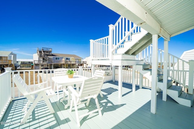 wooden terrace with outdoor dining space and stairway