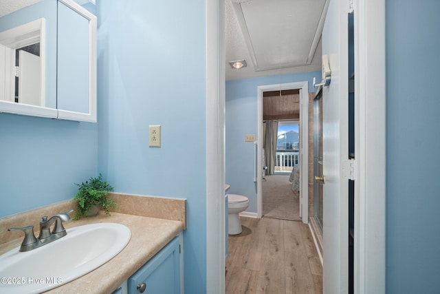 bathroom with toilet, wood finished floors, and vanity