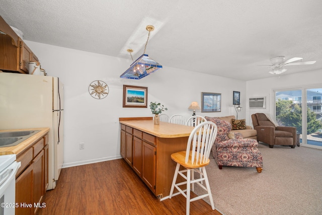 kitchen featuring open floor plan, light countertops, brown cabinetry, and stove