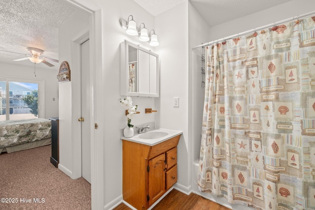 bathroom featuring ensuite bathroom, ceiling fan, a textured ceiling, vanity, and baseboards