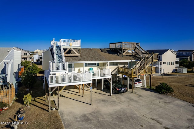 back of house with stairs, roof with shingles, and a residential view