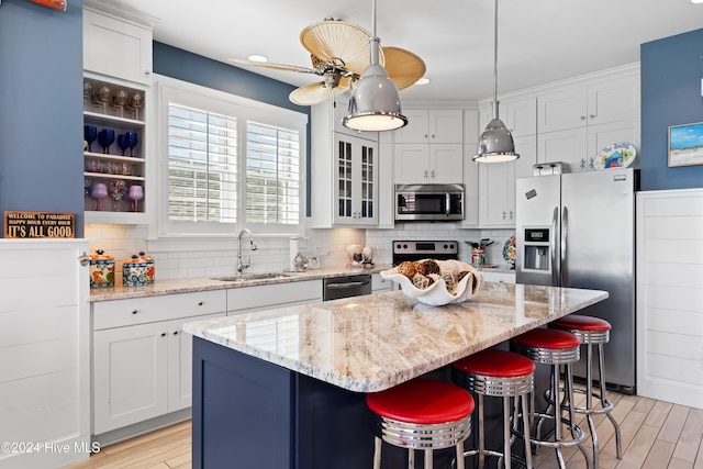 kitchen featuring appliances with stainless steel finishes, white cabinetry, a kitchen island, and sink