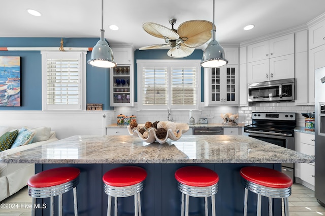 kitchen featuring a kitchen bar, white cabinets, a spacious island, and appliances with stainless steel finishes