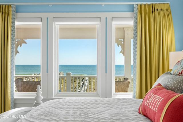 bedroom featuring a water view and a beach view