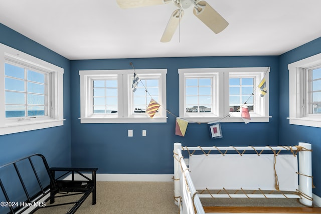 carpeted bedroom featuring multiple windows and ceiling fan