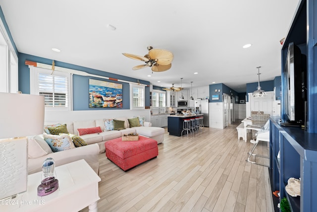 living room with ceiling fan, plenty of natural light, and light wood-type flooring