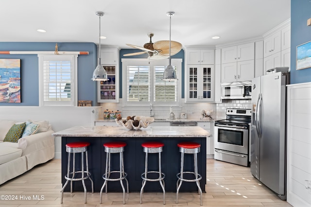 kitchen featuring white cabinetry, stainless steel appliances, tasteful backsplash, light stone counters, and light hardwood / wood-style flooring