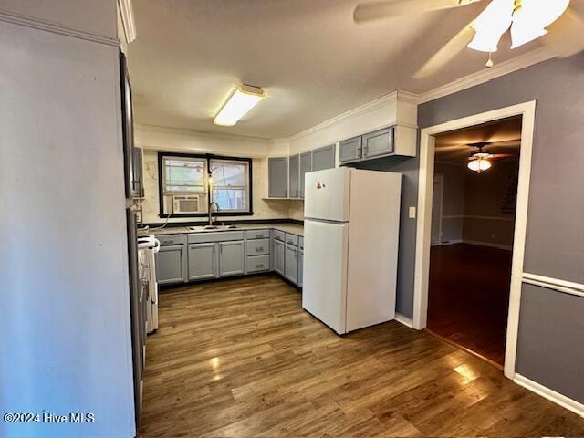 kitchen with gray cabinetry, white fridge, dark wood-type flooring, and ornamental molding