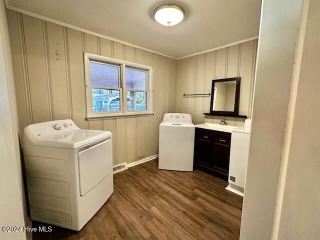 clothes washing area featuring separate washer and dryer, dark hardwood / wood-style floors, crown molding, and sink