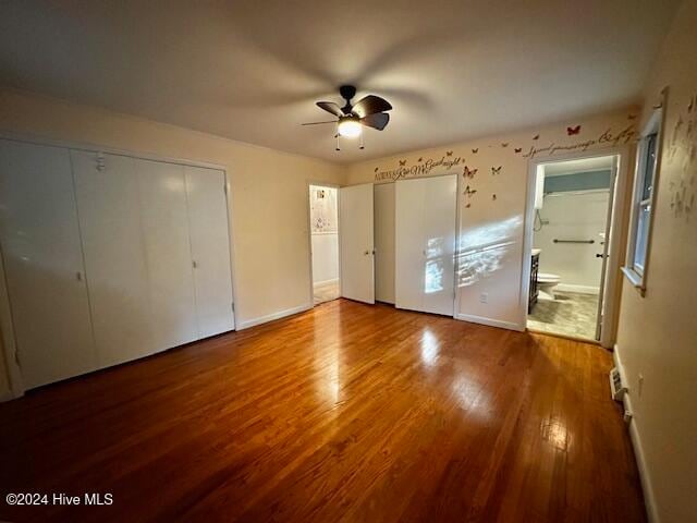 unfurnished bedroom featuring hardwood / wood-style floors, ensuite bath, and ceiling fan