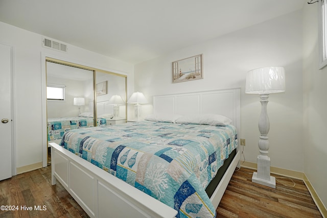 bedroom with dark wood-type flooring and a closet