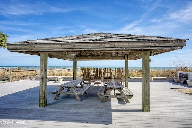 wooden terrace with a gazebo, a water view, and a beach view