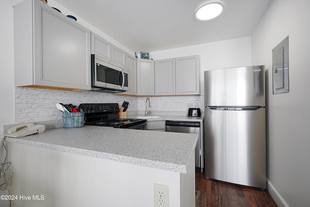 kitchen with kitchen peninsula, appliances with stainless steel finishes, tasteful backsplash, sink, and dark hardwood / wood-style floors