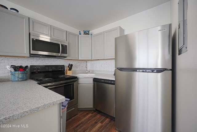 kitchen featuring sink, dark hardwood / wood-style flooring, backsplash, gray cabinets, and appliances with stainless steel finishes