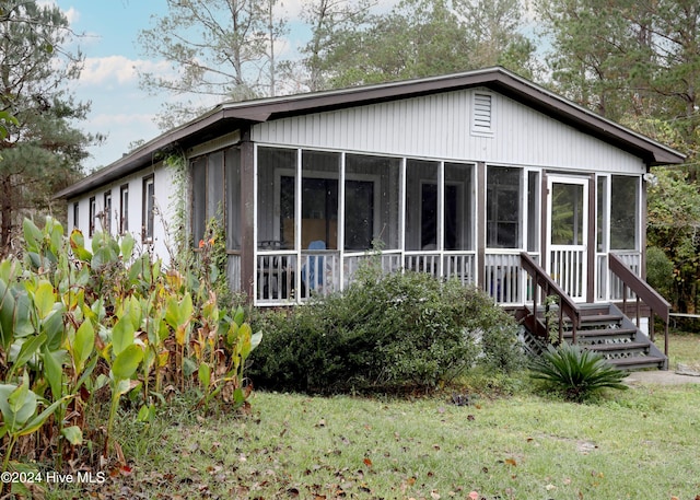 back of property featuring a yard and a sunroom