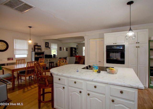 kitchen with black appliances, a kitchen island, white cabinets, and hanging light fixtures