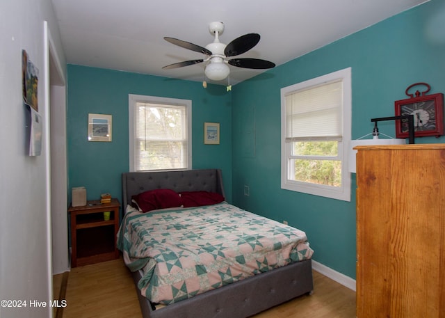 bedroom featuring light wood-type flooring, multiple windows, and ceiling fan