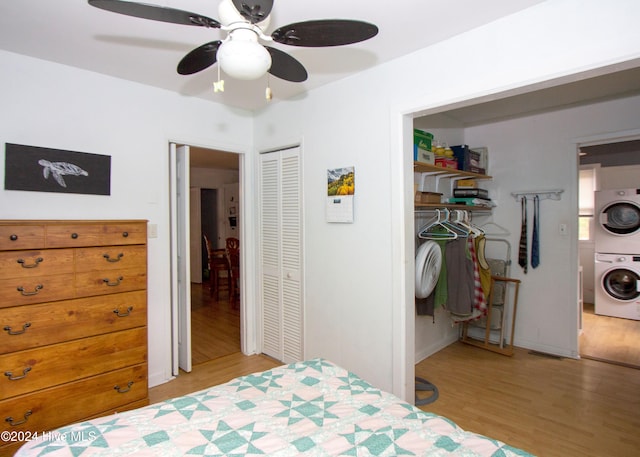 bedroom with ceiling fan, stacked washer / dryer, and light hardwood / wood-style flooring