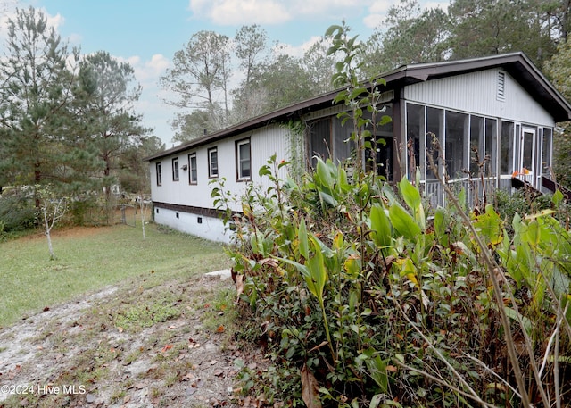 view of property exterior with a yard and a sunroom