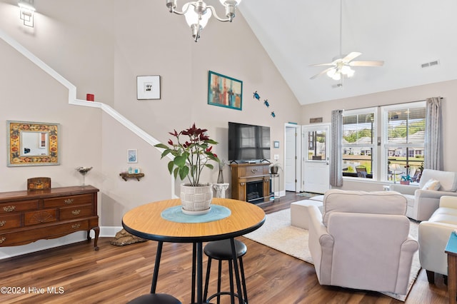 living room with ceiling fan with notable chandelier, high vaulted ceiling, and dark hardwood / wood-style floors