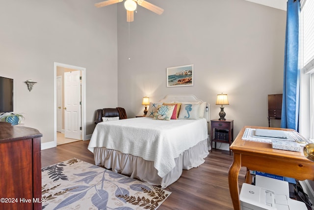 bedroom featuring dark hardwood / wood-style floors, ceiling fan, and a high ceiling