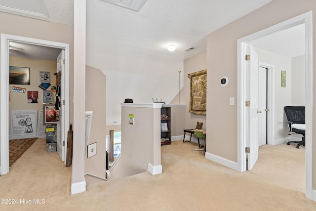 hallway featuring light carpet and a textured ceiling