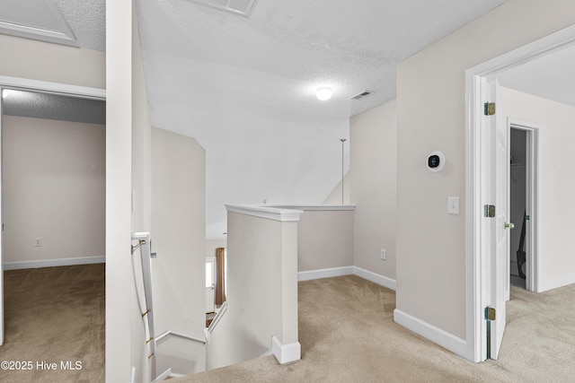 hallway with light carpet and a textured ceiling