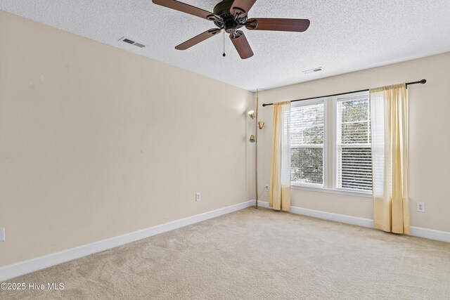 spare room with ceiling fan, light colored carpet, and a textured ceiling