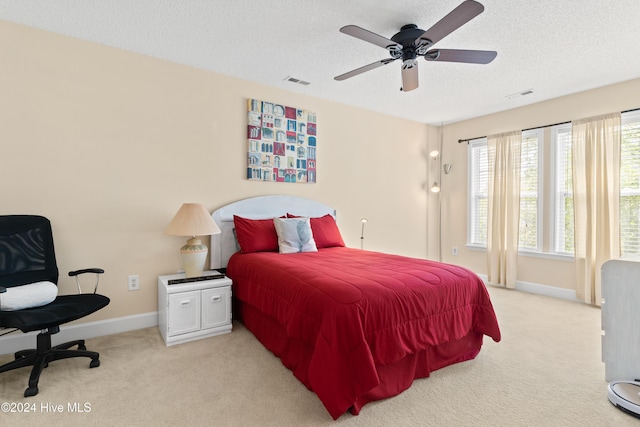 bedroom featuring ceiling fan, light colored carpet, and a textured ceiling