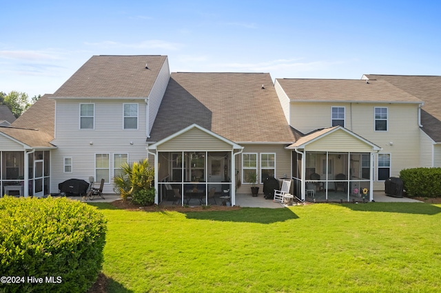 rear view of house with a sunroom, a lawn, and a patio area