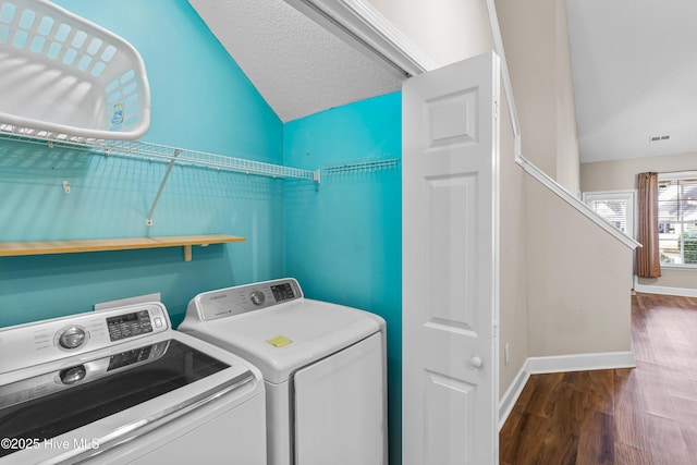 clothes washing area with hardwood / wood-style flooring, washer and dryer, and a textured ceiling