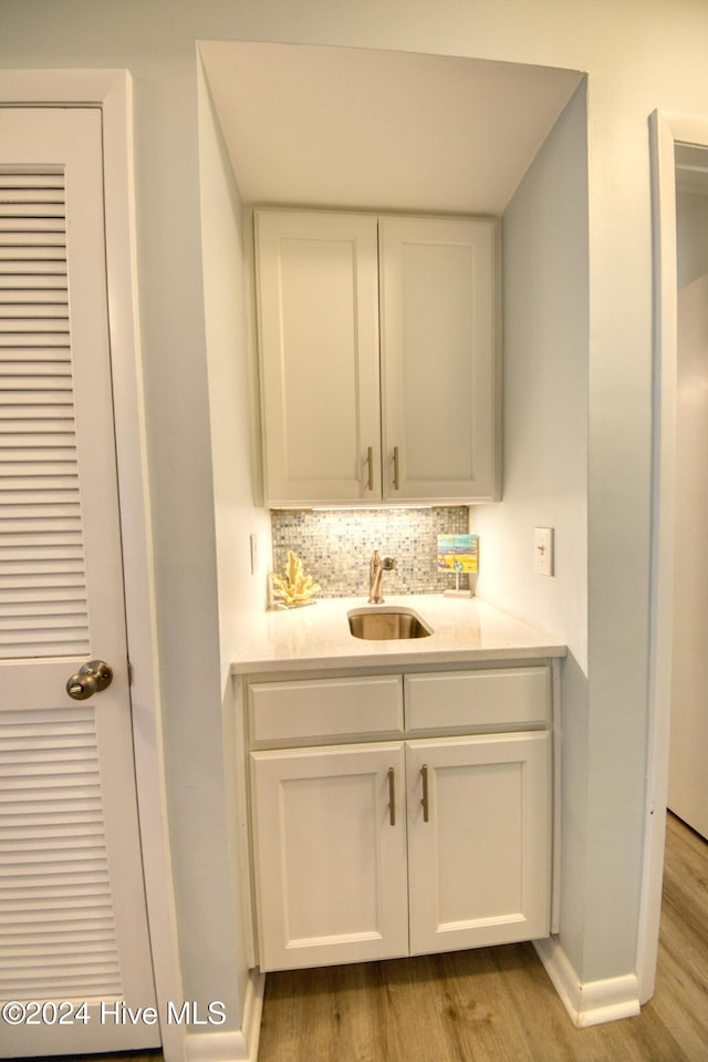 bar featuring tasteful backsplash, white cabinetry, sink, and light wood-type flooring