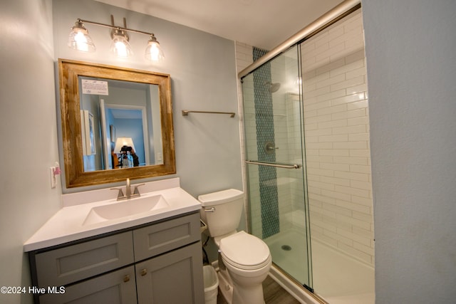 bathroom featuring vanity, toilet, and a shower with door