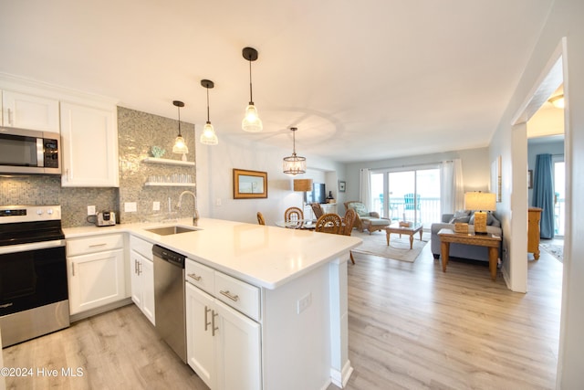 kitchen featuring white cabinetry, sink, kitchen peninsula, decorative backsplash, and appliances with stainless steel finishes