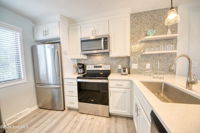 kitchen with white cabinets, appliances with stainless steel finishes, hanging light fixtures, and sink