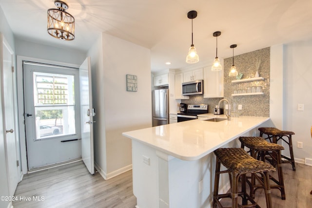 kitchen featuring kitchen peninsula, sink, light hardwood / wood-style flooring, appliances with stainless steel finishes, and white cabinetry