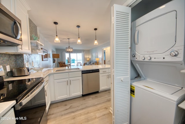 kitchen with appliances with stainless steel finishes, backsplash, white cabinetry, and stacked washer / drying machine