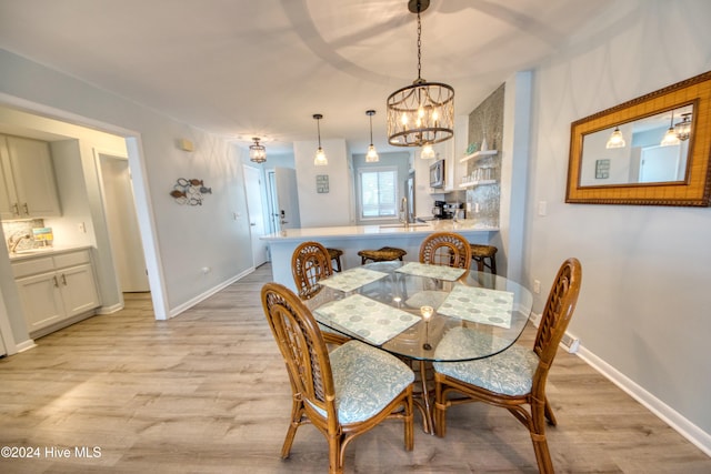 dining room featuring light wood-type flooring, sink, and an inviting chandelier