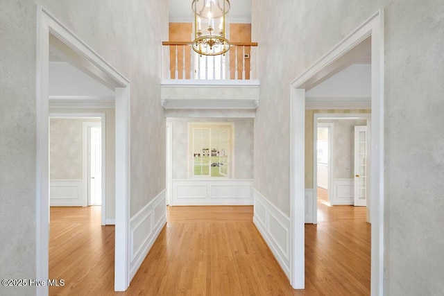 foyer entrance featuring light hardwood / wood-style floors, an inviting chandelier, a healthy amount of sunlight, and crown molding