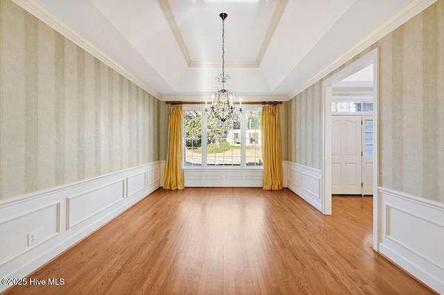 unfurnished dining area with a tray ceiling, hardwood / wood-style floors, and a chandelier