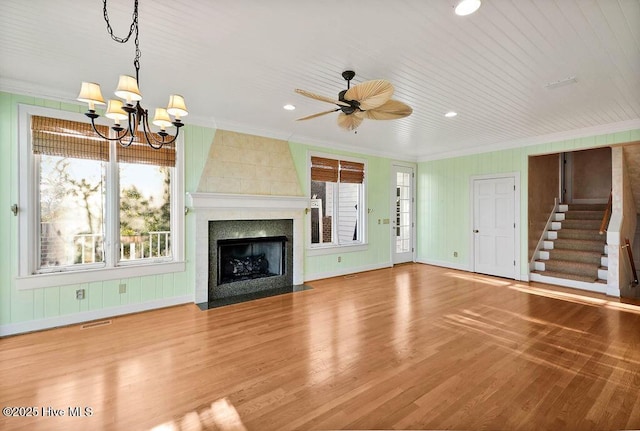 unfurnished living room featuring hardwood / wood-style flooring, ceiling fan with notable chandelier, a large fireplace, and ornamental molding