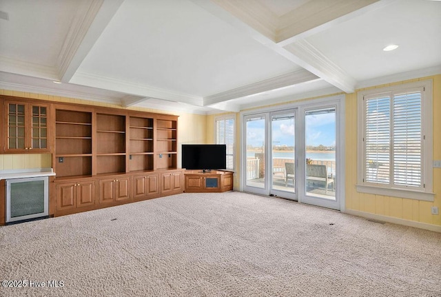 unfurnished living room featuring beamed ceiling, carpet floors, and ornamental molding