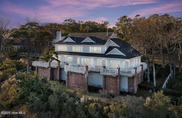 back house at dusk with a balcony and cooling unit