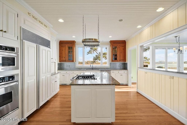 kitchen with pendant lighting, a center island, crown molding, white cabinetry, and a chandelier