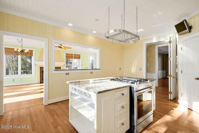 kitchen with ceiling fan with notable chandelier, light hardwood / wood-style floors, ornamental molding, and stainless steel range