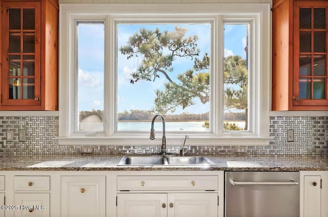 kitchen featuring light stone counters, stainless steel dishwasher, sink, a water view, and white cabinets